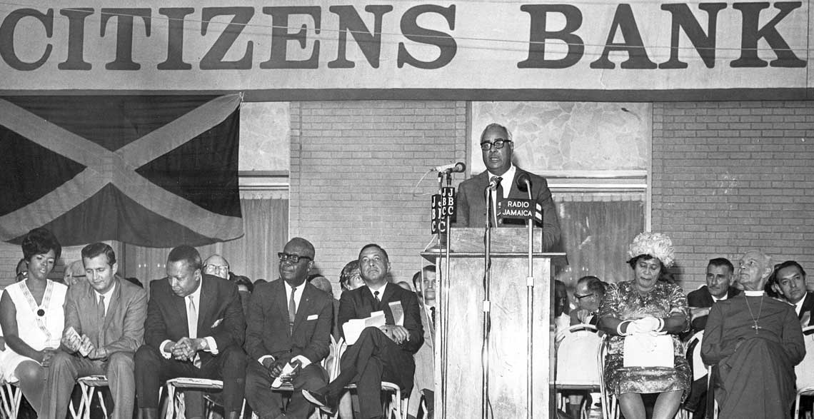 Optimism: Launching Citizens Bank in 1968, Hon. Russell Graham, Custos of St. Andrew and Board Chairman of the bank speaks of its intention to “try in every way to improve the economy”. Front row from left: Mrs. Seaga, the Hon. Edward Seaga, Minister of Finance and Planning, Prime Minister, the Hon. Hugh Shearer, Governor General, Sir Clifford Campbell, Mr. William F. Smith, a director of the Bank and master of ceremonies, Lady Campbell and the Anglican Bishop of Jamaica, the Rt. Rev. J. C. Swaby. © 1968 The Gleaner