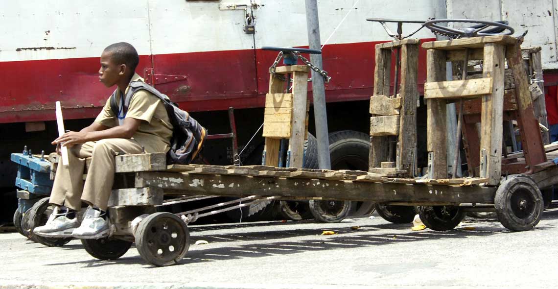 Schoolboy relaxes on one of the haulage carts chained together for safety at Coronation Market. © The Gleaner 